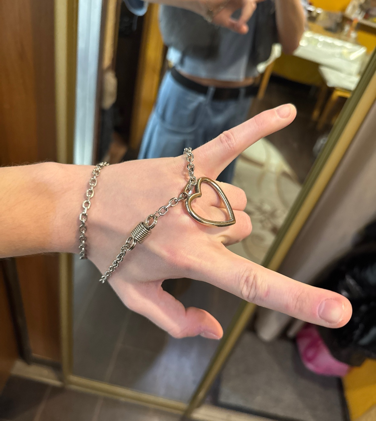 A hand is adorned with a silver chain bracelet featuring a heart-shaped charm. The caption suggests a theme of being 'in chains of love'.