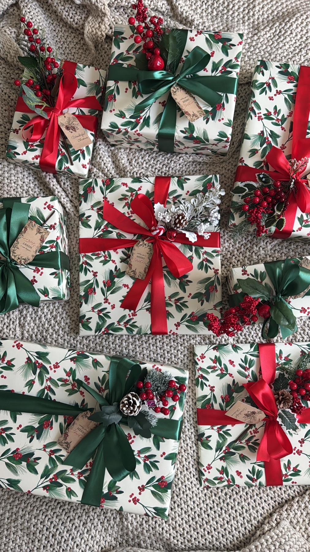 Several beautifully wrapped gifts are arranged on a soft, textured surface. Each present is adorned with festive ribbons and decorative accents, creating a visually appealing display.