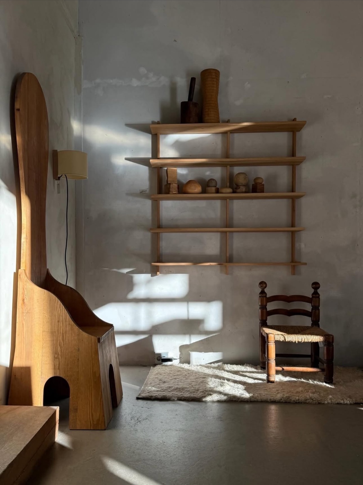 A minimalist interior with unique wooden furniture and shelves. The photo highlights the interplay of light and shadow.