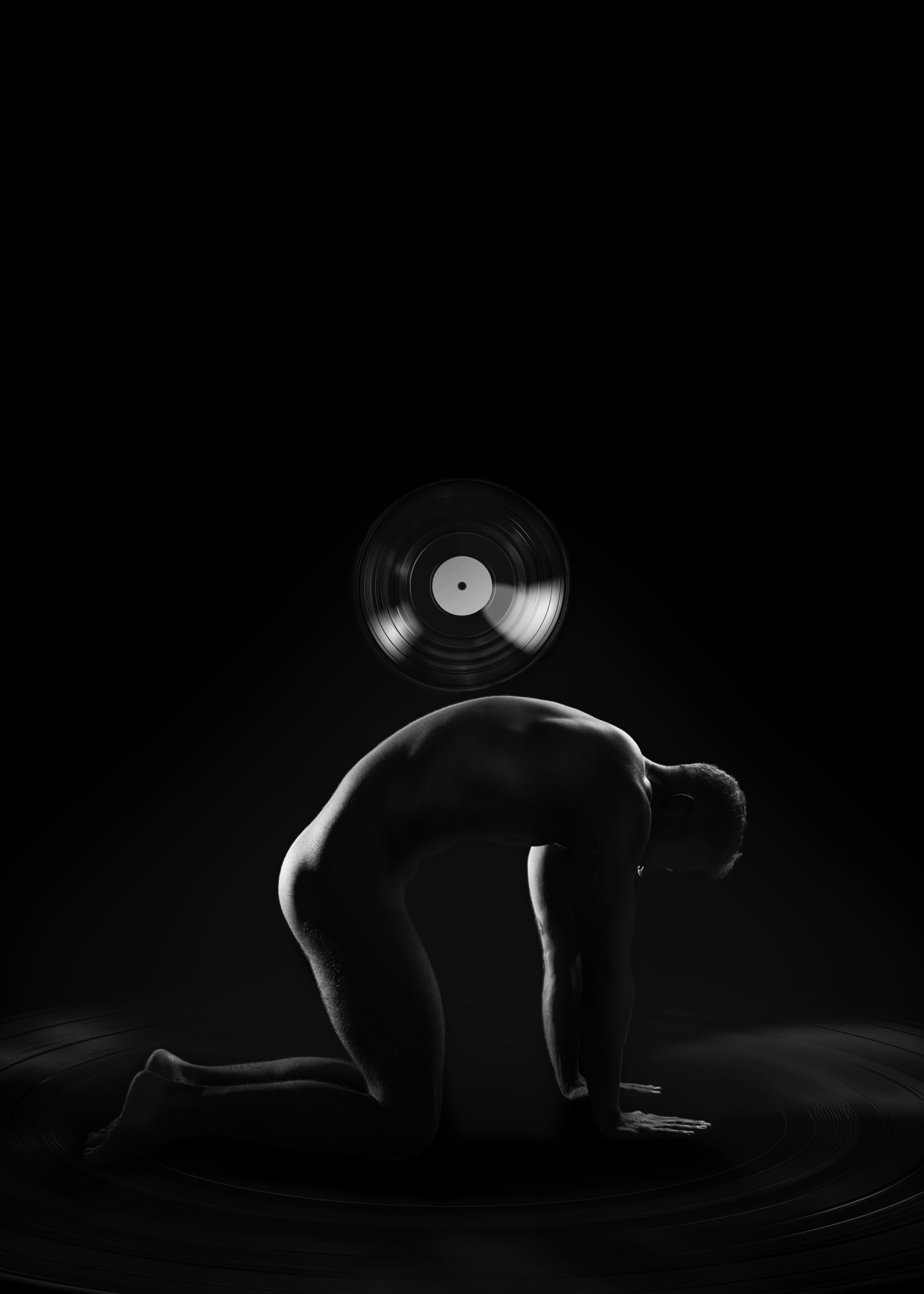 A black and white artistic silhouette of a man in a yoga pose, reminiscent of a cat, with a vinyl record suspended above him.