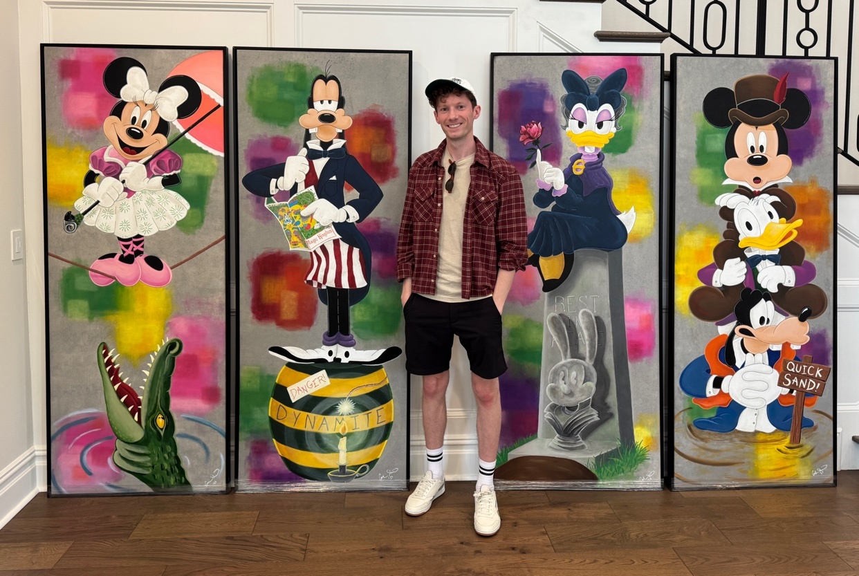 A man poses in front of a series of colorful paintings featuring Disney characters. The artwork is modern and vibrant.