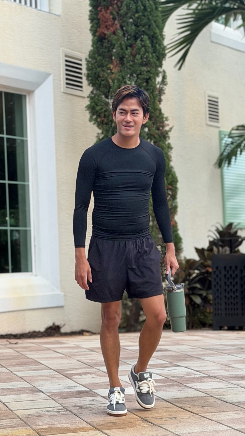 A man in athletic wear poses outdoors with a water bottle in hand, indicating he is focused on his workout.