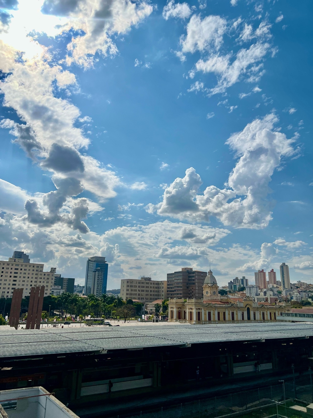 A bright, sunny day with dramatic clouds over a cityscape featuring historic and modern buildings.