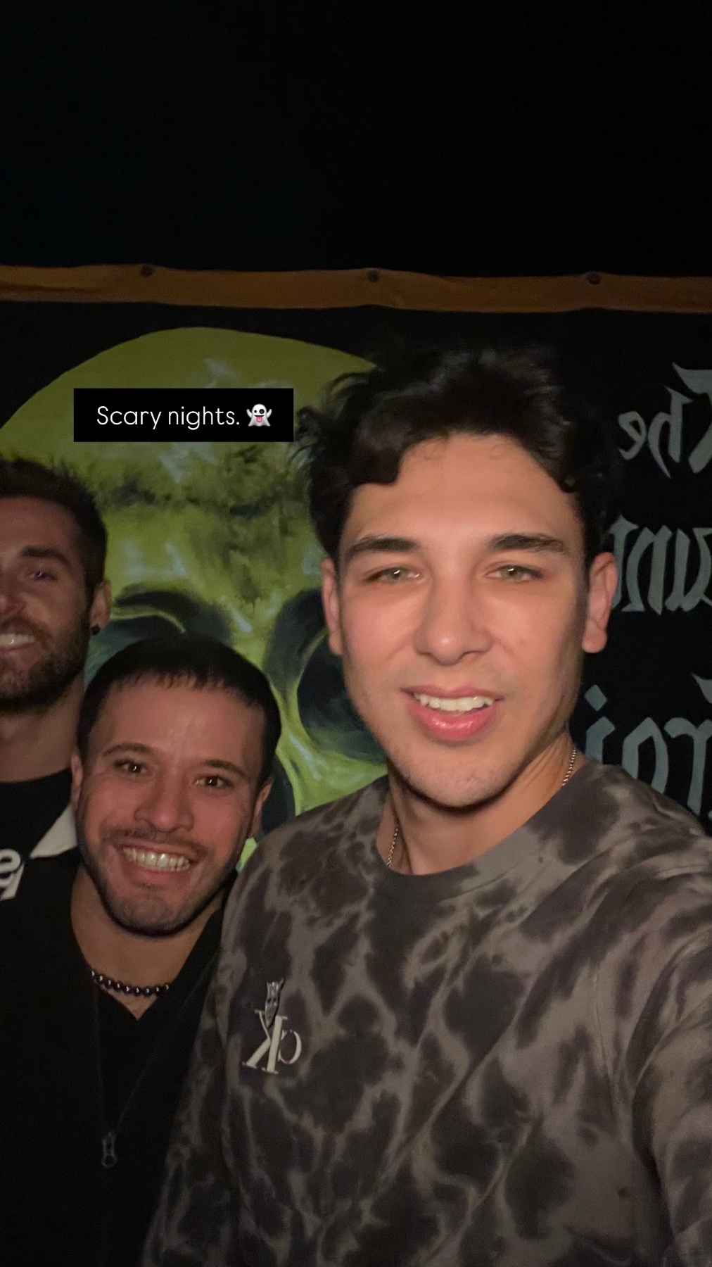A selfie of three men smiling at the camera. They appear to be at a Halloween event.