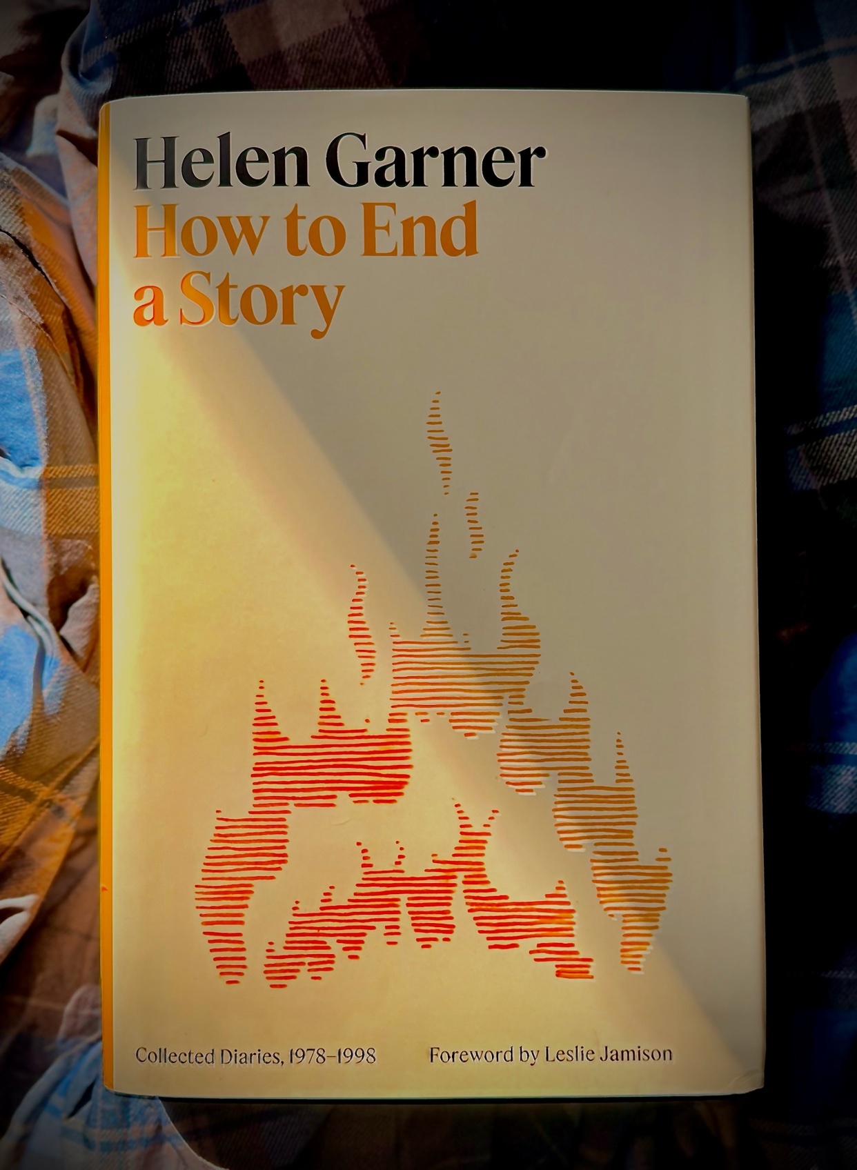 The cover of Helen Garner's book "How to End a Story" features an illustration of stylized flames in orange and red hues against a cream background. The title and author's name are prominently displayed in black and orange text.