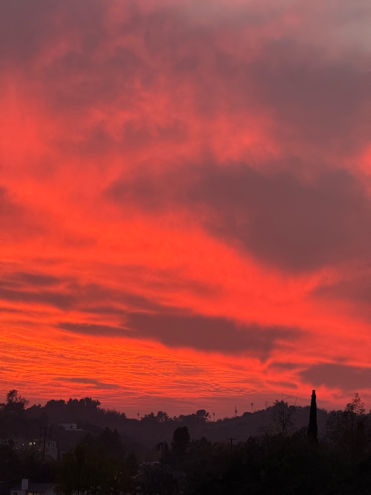 A vibrant sunset paints the sky with fiery hues of red and orange. The clouds are dramatically lit, creating a stunning landscape.
