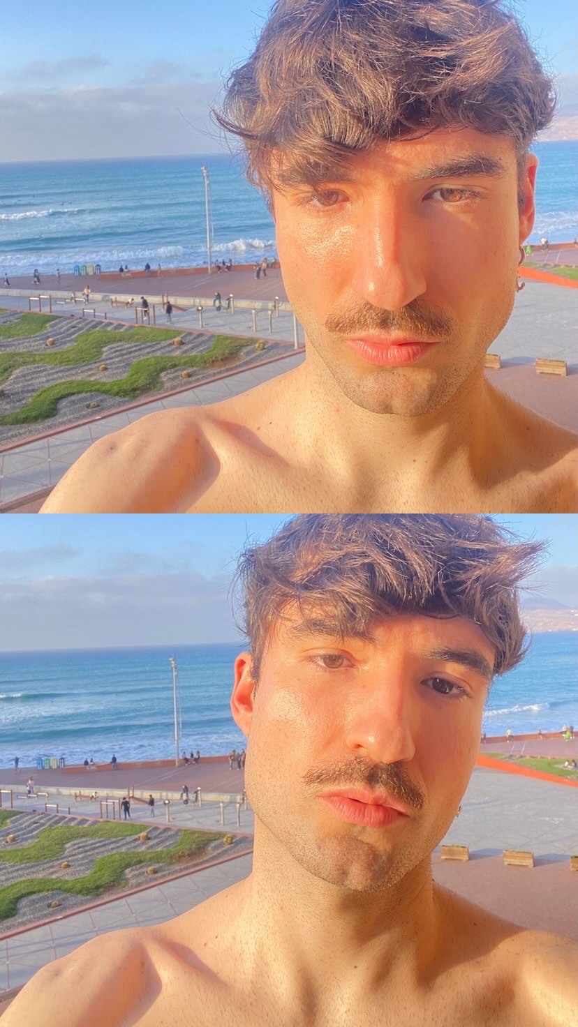 A shirtless man poses for a selfie with the ocean in the background. The photo is taken in Gran Canaria.