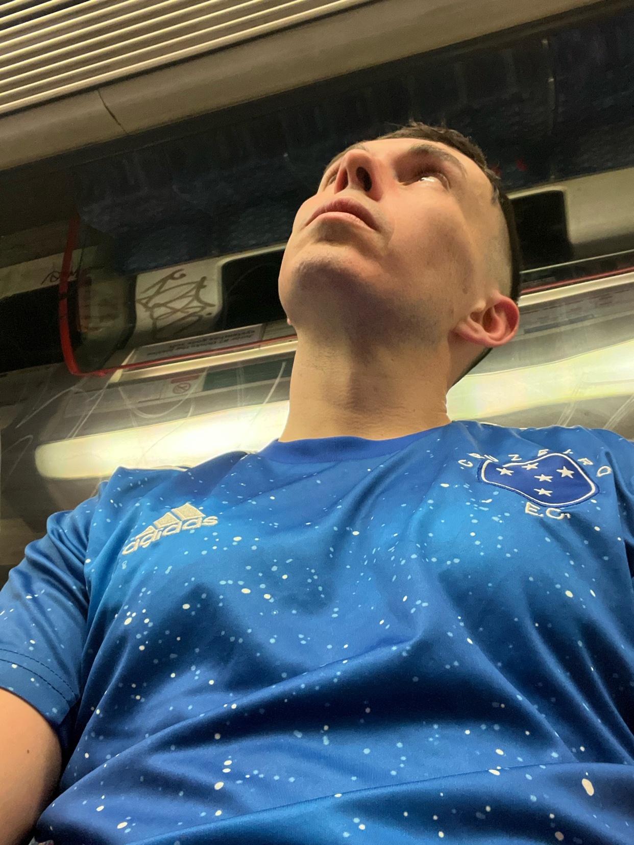A man in a blue sports jersey looks up. The photo is taken from a low angle.