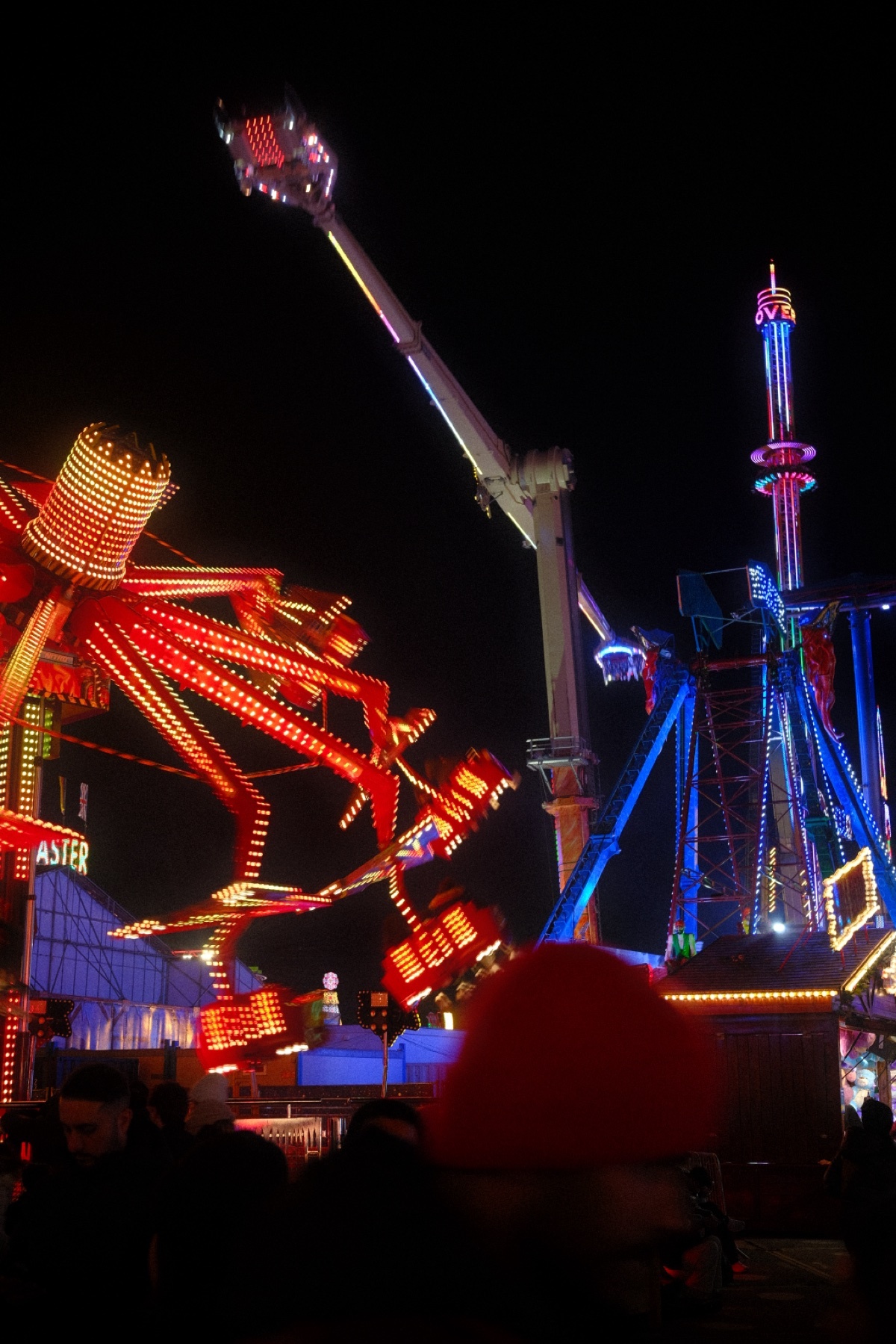 A nighttime shot of a carnival with brightly lit rides. The photo captures the energy and excitement of the amusement park.