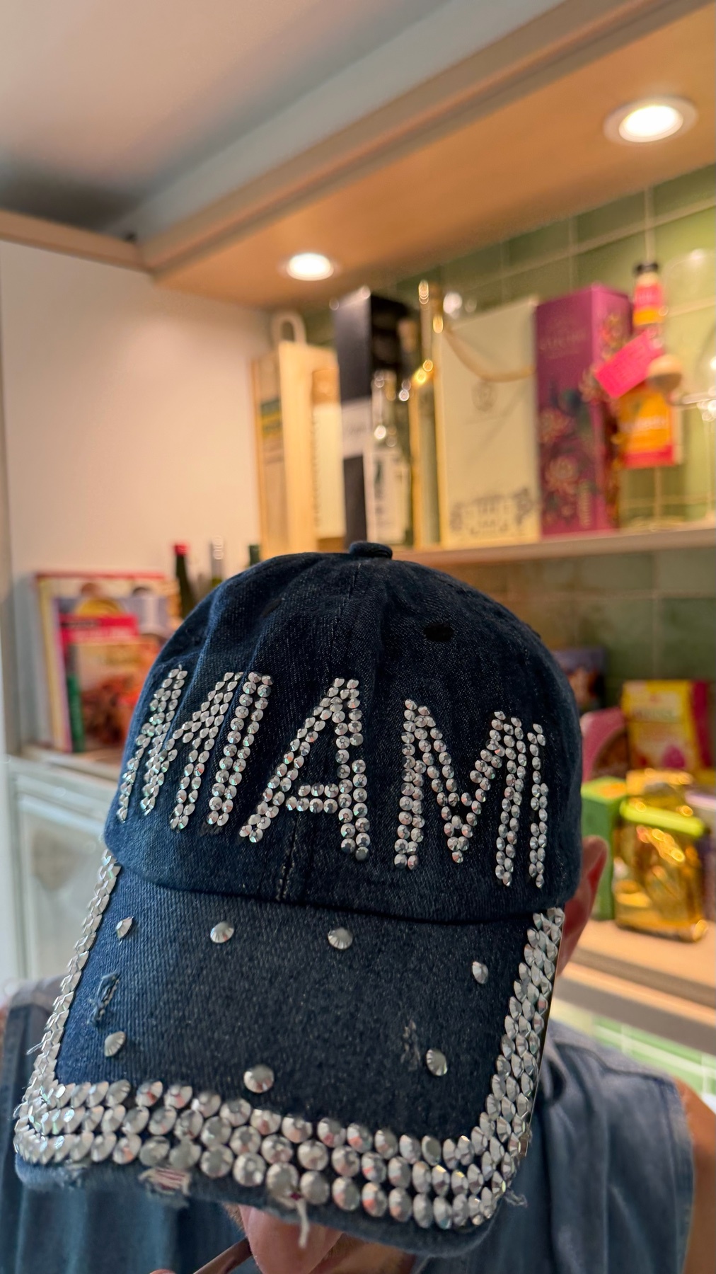 A close-up shot of a denim baseball cap adorned with rhinestones that spell out "MIAMI" across the front and along the brim.