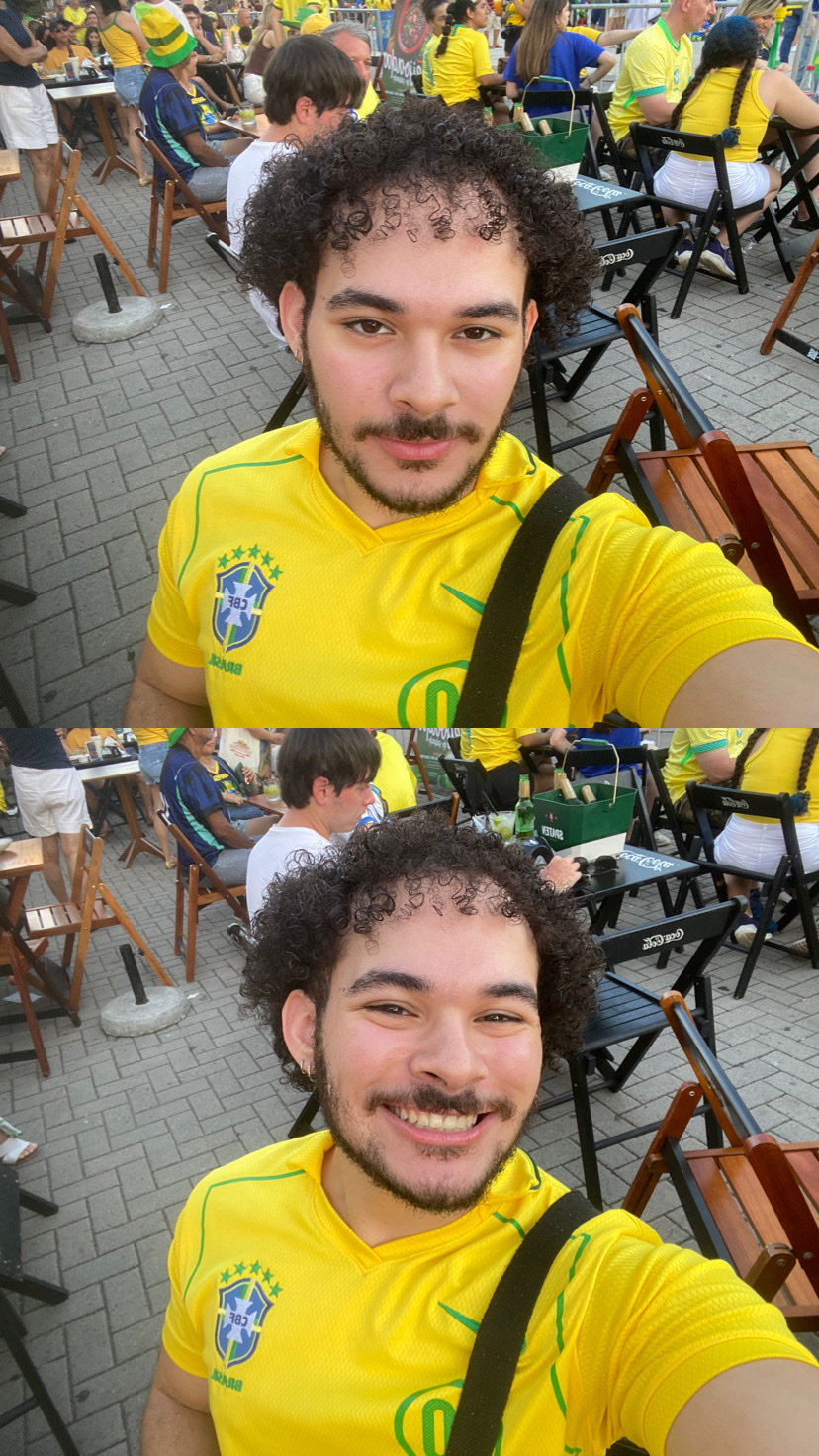 A man with curly hair and a mustache smiles at the camera in a two-part selfie. He is wearing a yellow Brazil national football team jersey and is seated outdoors with a crowd in the background.
