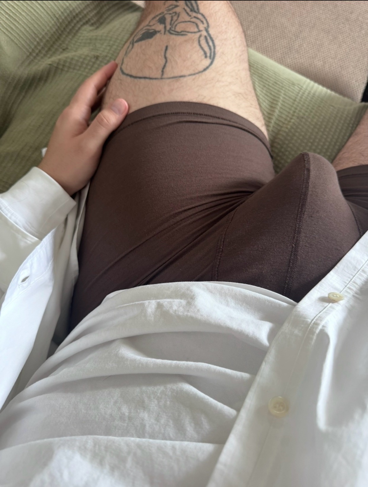 A man is seen wearing brown underwear and a white shirt. The photo is taken from a first-person perspective.