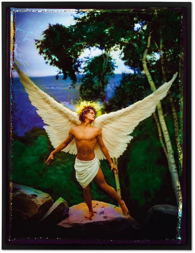 A digital art piece depicts a man with large white wings, a halo, and a white cloth around his waist. The man is standing in front of a forest and a body of water.