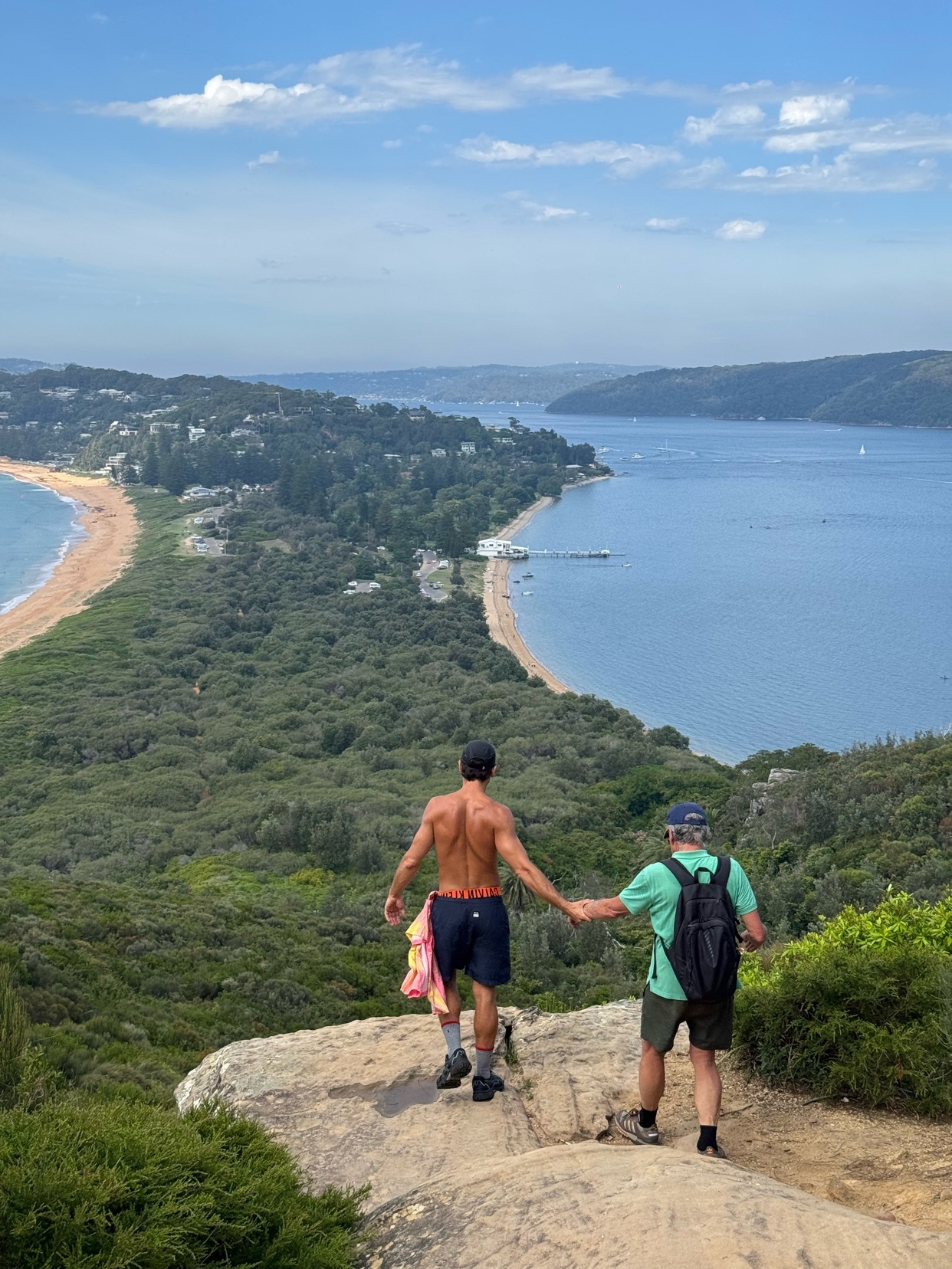 A couple holds hands while overlooking a beautiful beach and ocean view. The photo captures a moment of connection and the beauty of nature.