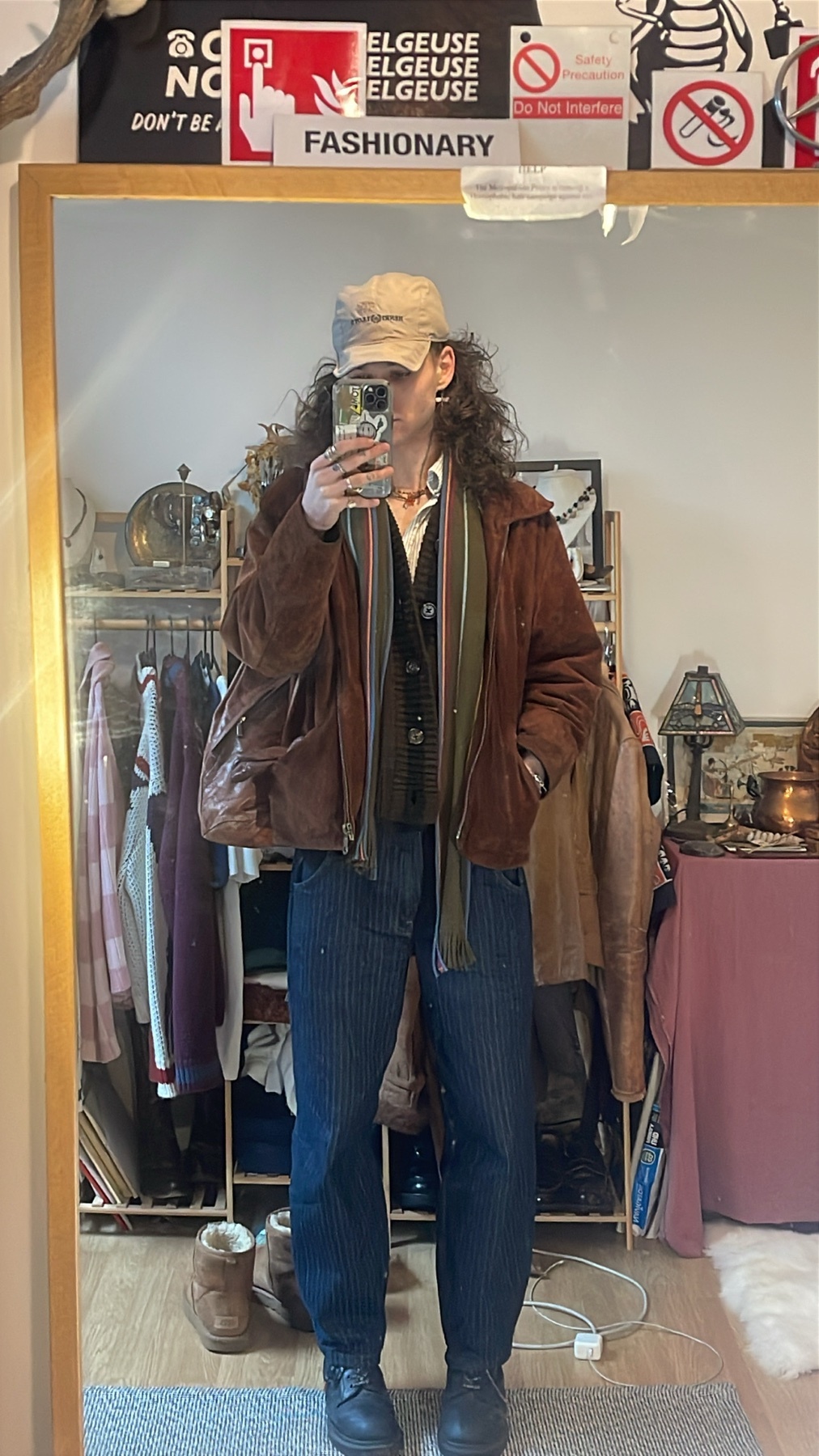 A man takes a mirror selfie, showcasing a vintage-inspired outfit. The photo highlights his curly hair, glasses, and stylish ensemble.