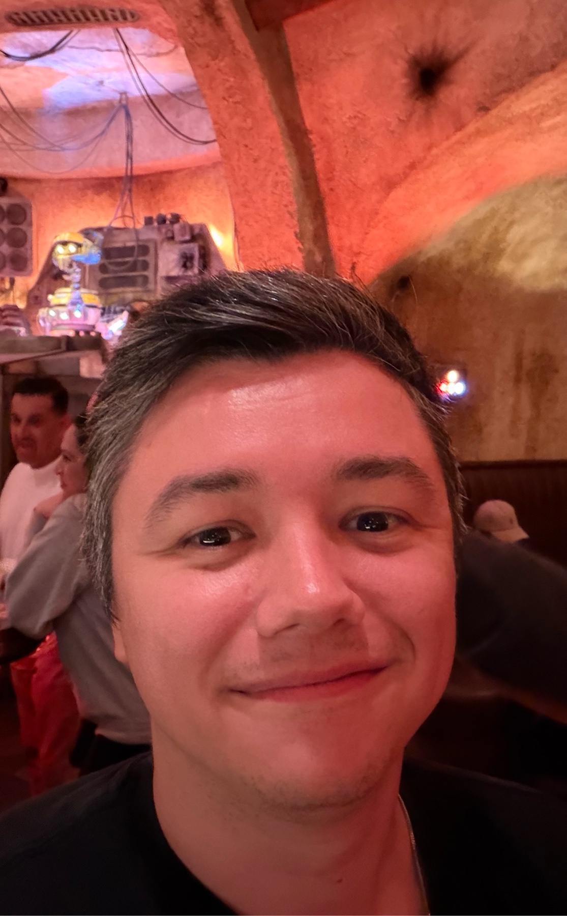 A man takes a selfie in a restaurant. He is smiling at the camera.
