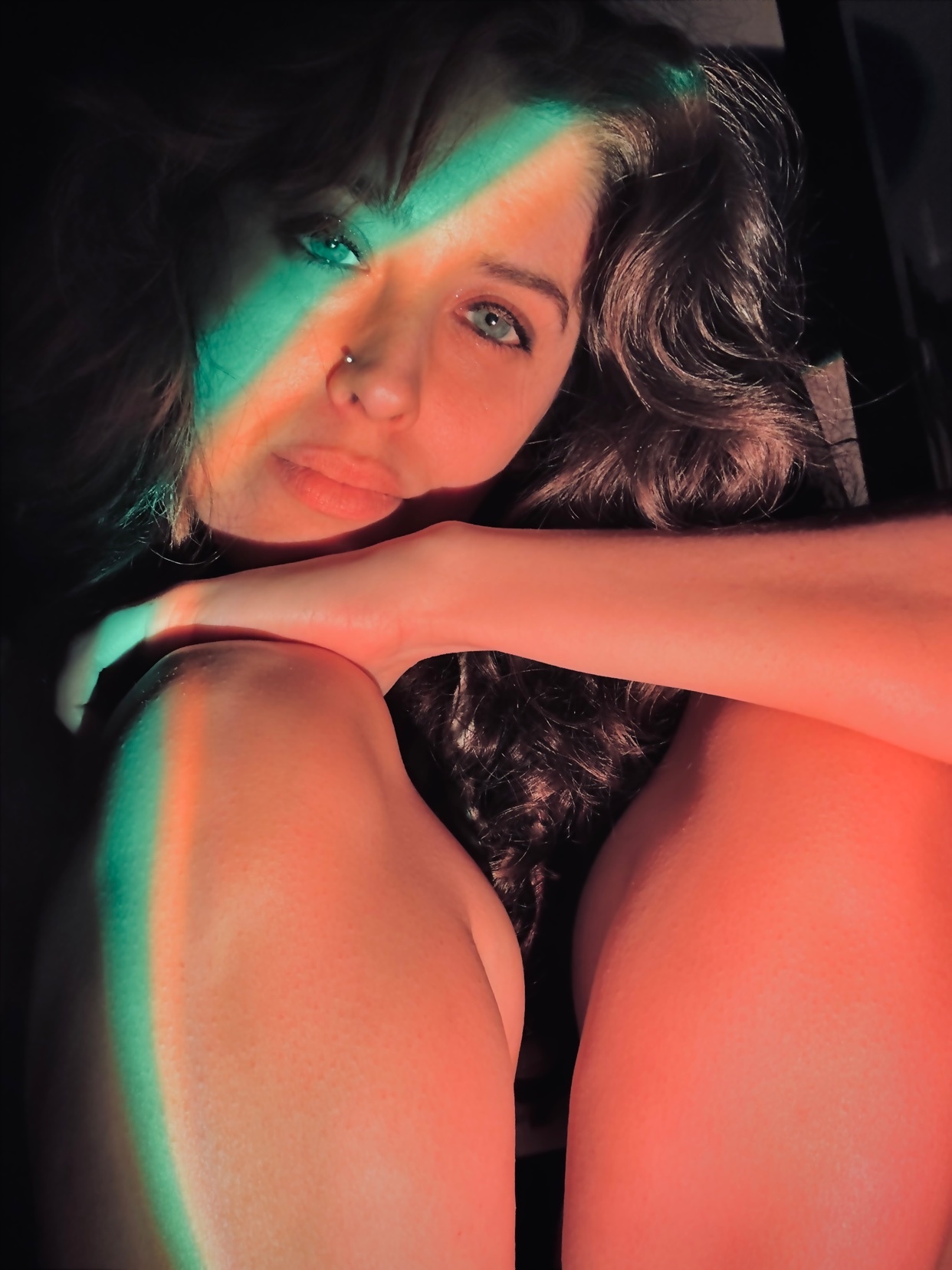 A woman poses for a portrait, illuminated by colorful light streaks. The image has an artistic and modern aesthetic.
