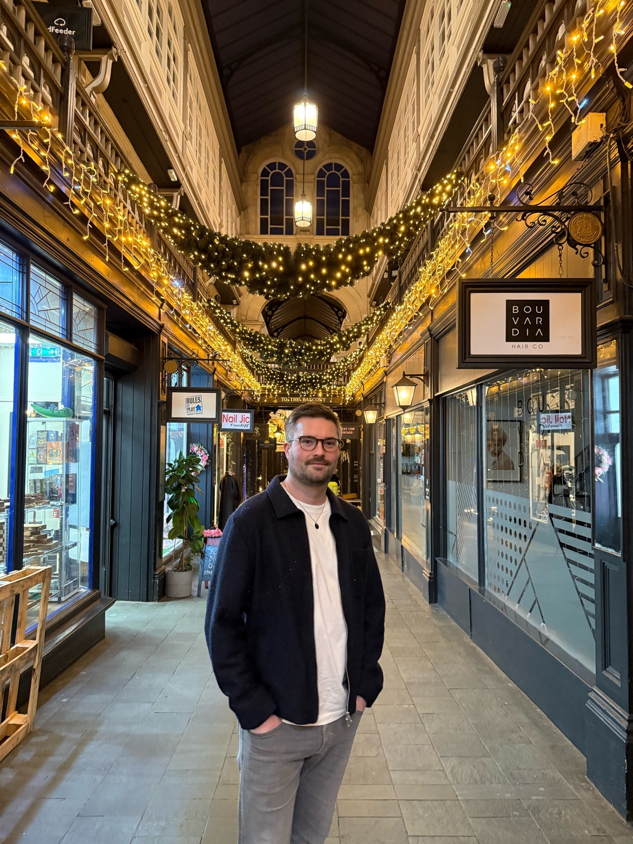 A man stands in a beautifully decorated shopping arcade. The image showcases the architecture and design of the space.