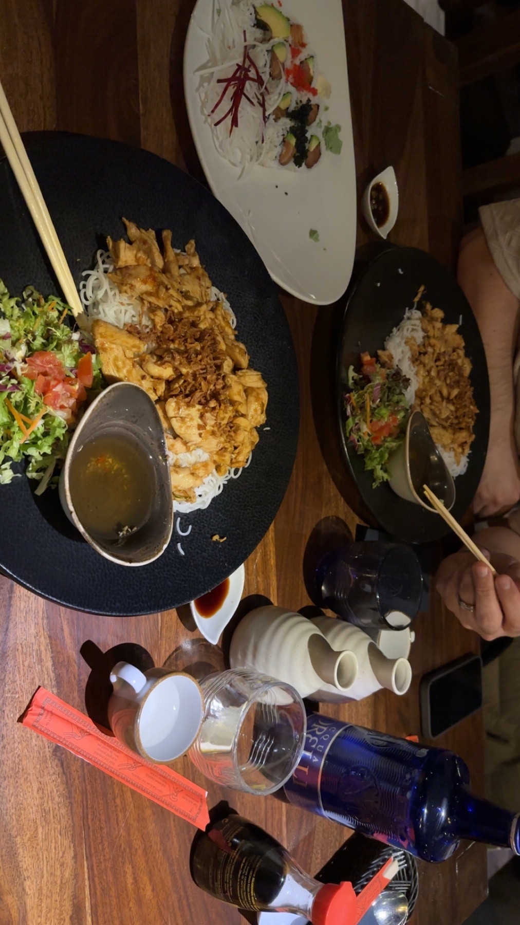A table set for a romantic dinner, featuring plates of food, chopsticks, and drinks. The photo captures the ambiance of a date night.