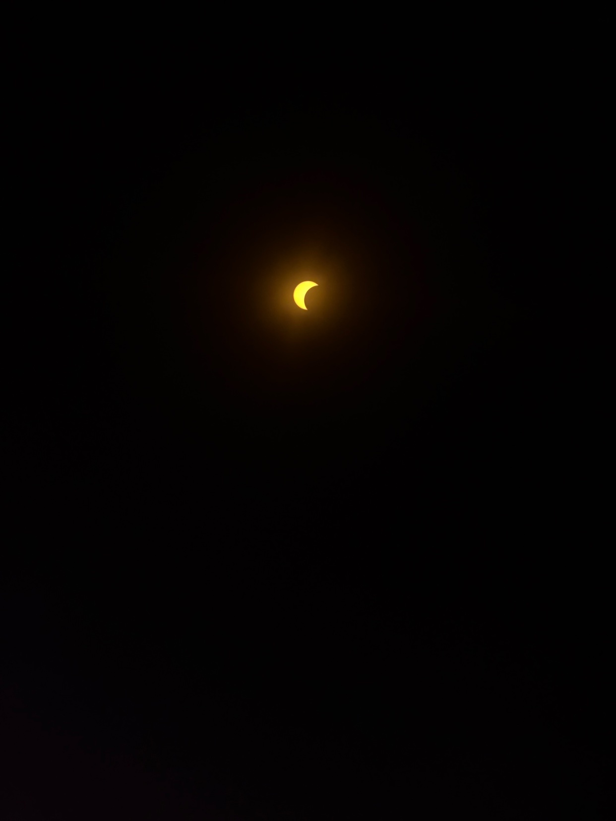 A partial solar eclipse is visible in the dark night sky, with a bright crescent sun partially obscured.