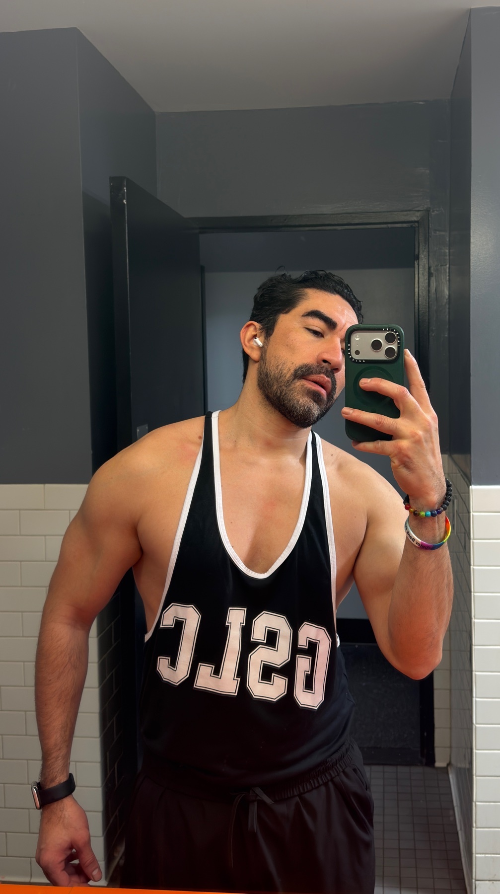 A man takes a mirror selfie after a workout. He is shirtless and flexing his muscles.