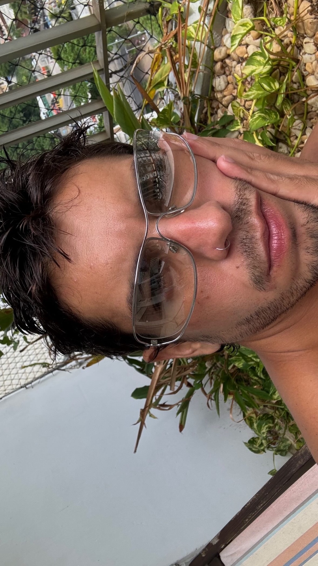 A man wearing sunglasses poses for a selfie outdoors.