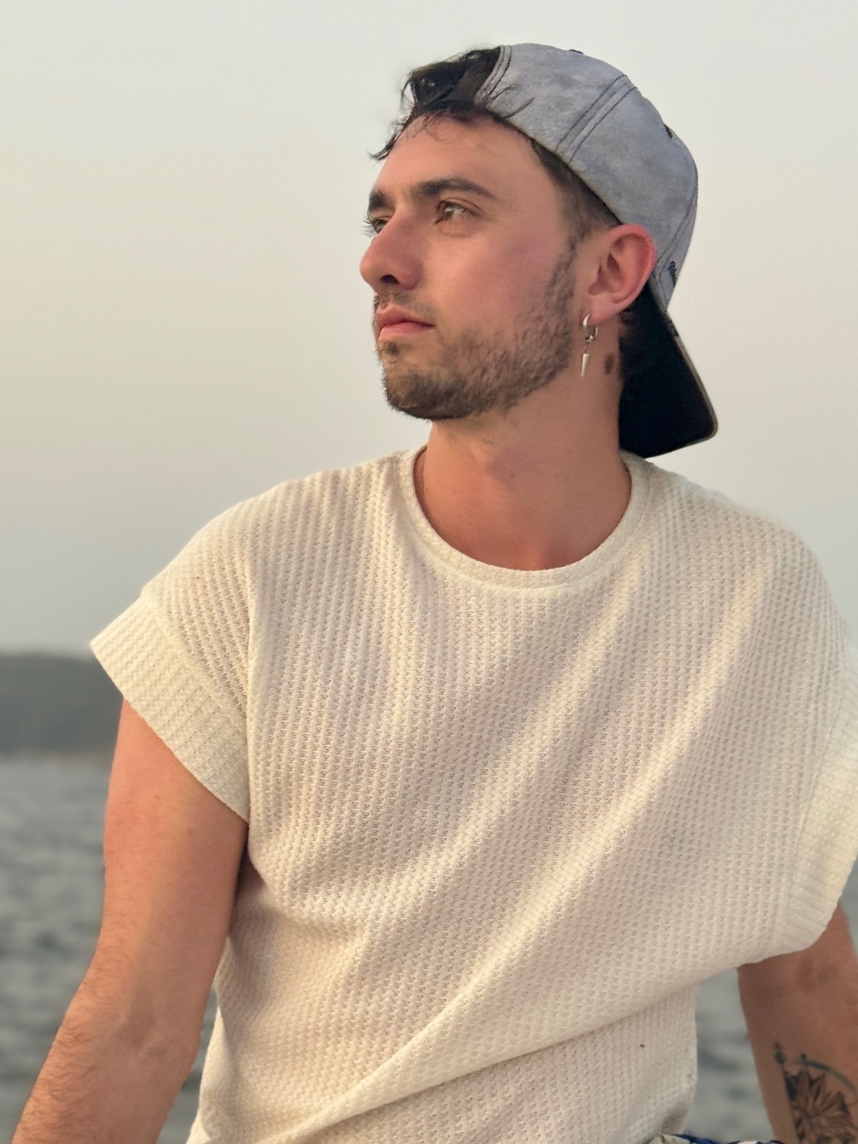 A man wearing a cap and white shirt poses on a boat. The photo is taken outdoors during the day.