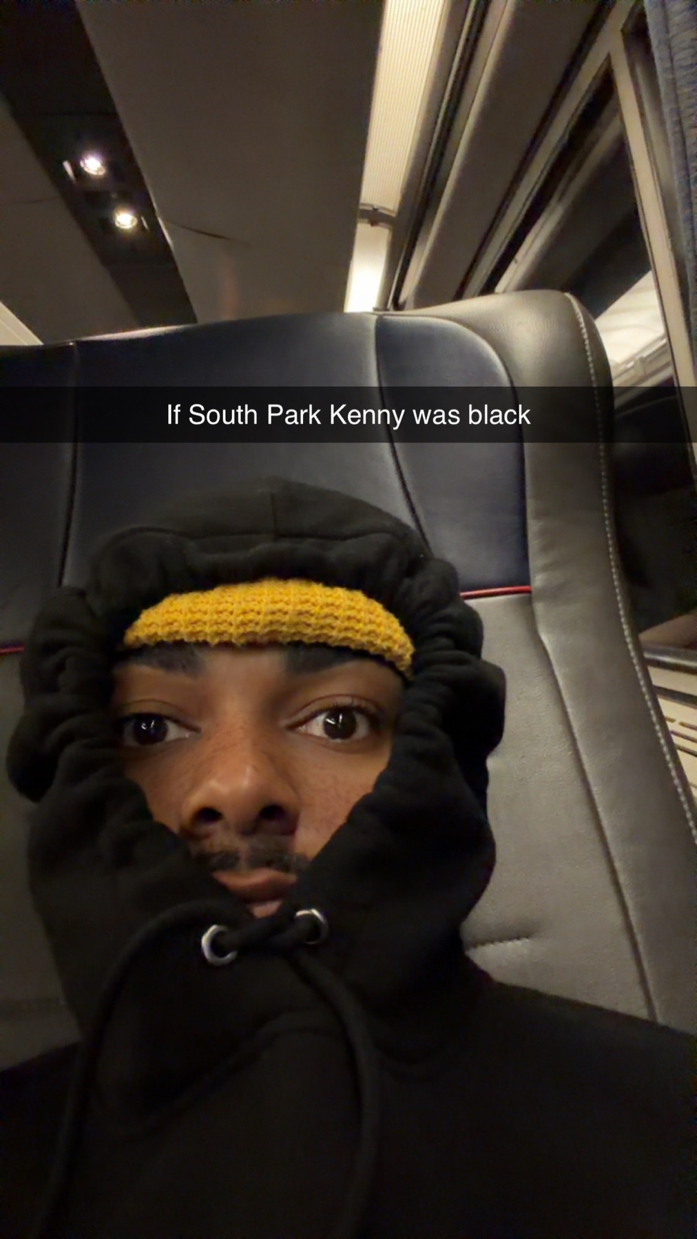 A selfie of a Black man wearing a black hoodie and a yellow beanie, with text overlay referencing South Park's Kenny.