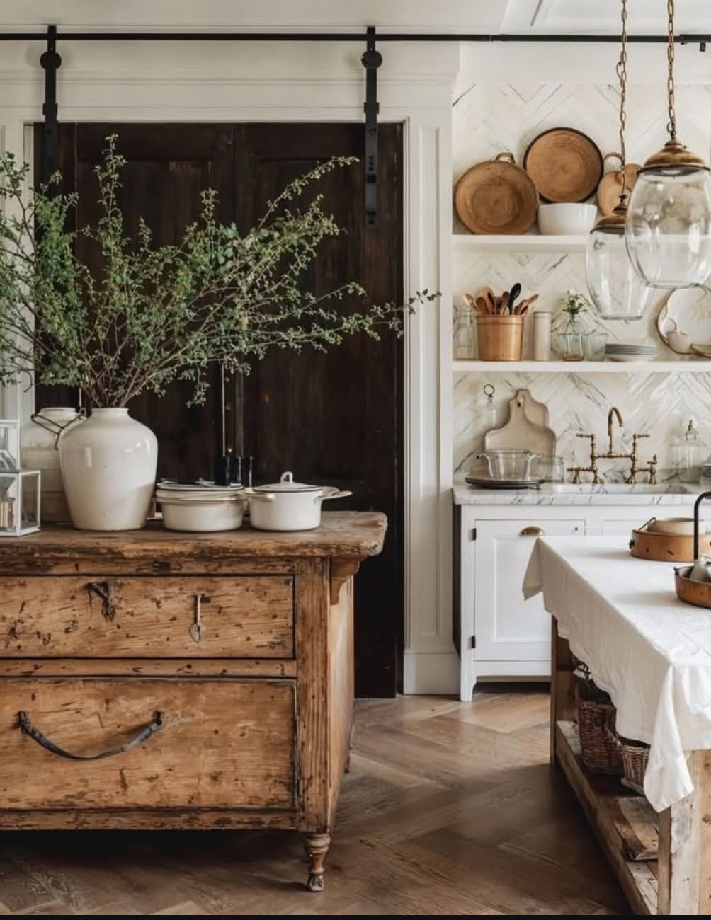 A rustic kitchen with wooden furniture, shelves, and vintage decor. The space is well-lit and features a farmhouse aesthetic.