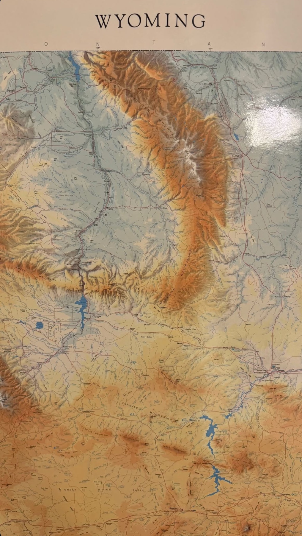 A close-up view of a topographic map of Wyoming, showing mountains, rivers, and lakes.
