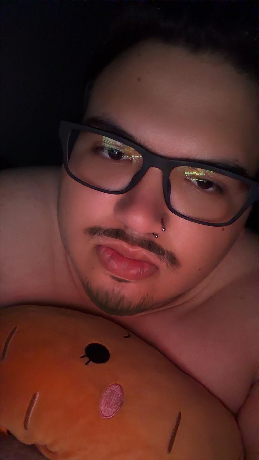 A close-up, low-angle shot of a man wearing glasses and holding a plush toy.