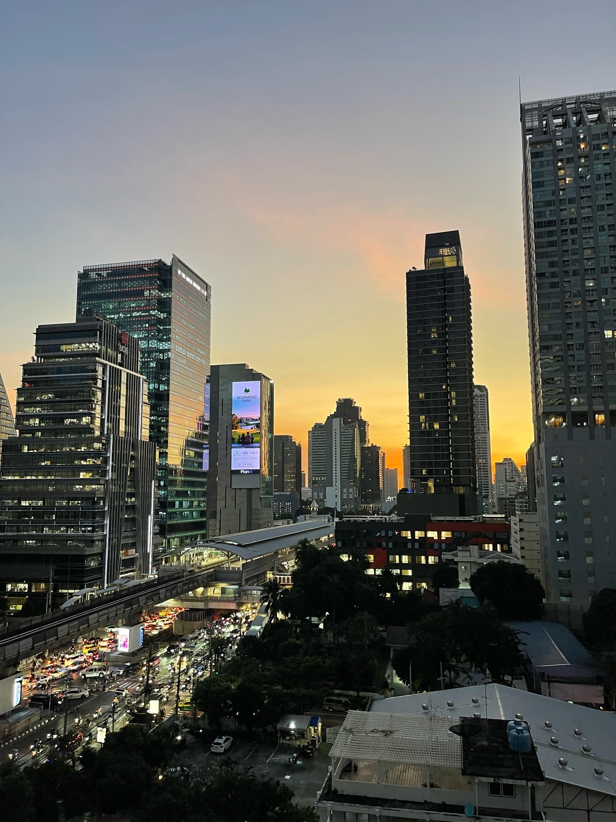 A stunning cityscape of Bangkok at sunset. The image captures the towering skyscrapers and vibrant sky.