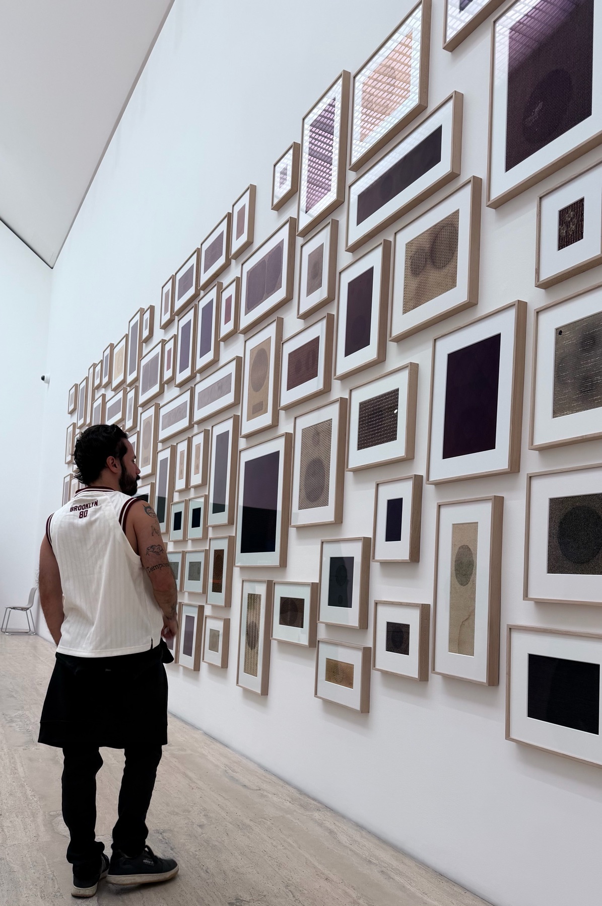 A man stands in an art gallery, admiring a wall of framed artwork. The image captures the intersection of art and human appreciation.