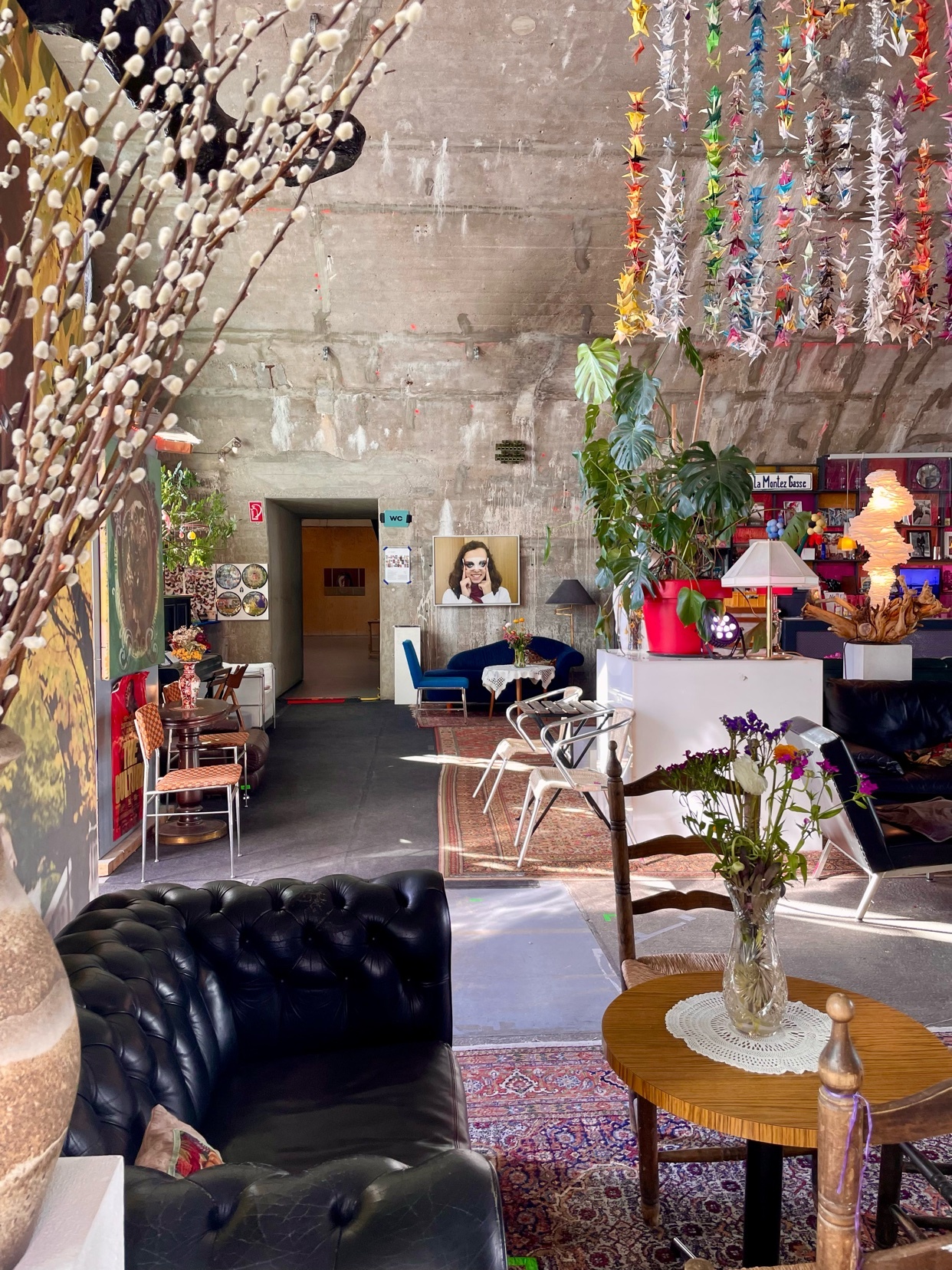 An eclectic and bohemian living space is filled with vintage furniture, lush indoor plants, and vibrant, colorful decor. The space features a mix of textures and patterns, creating a unique and artistic atmosphere.