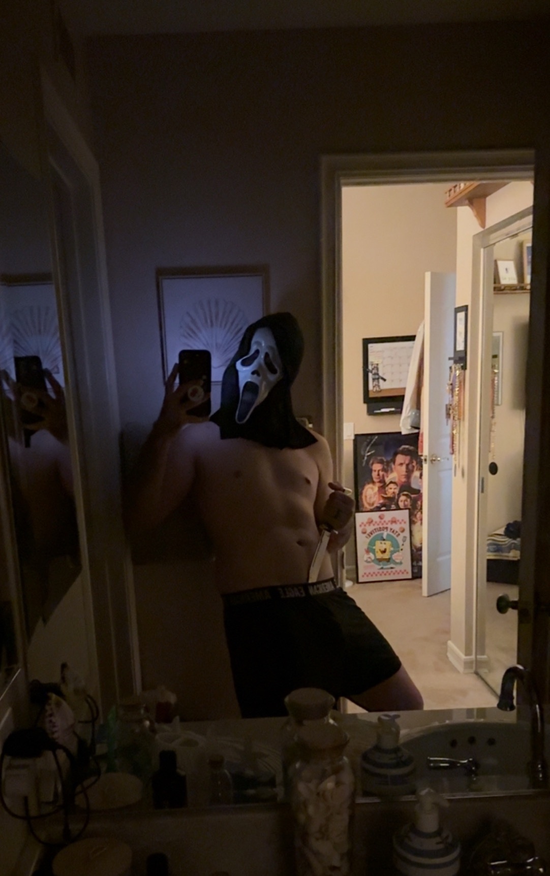 A man in a Scream mask takes a shirtless mirror selfie. The post references the movie "Scream".