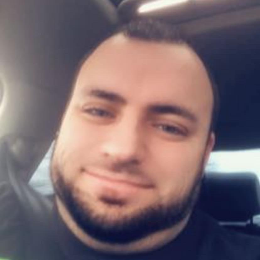 A close-up selfie of a man with a beard, looking towards the camera with a slight smile.