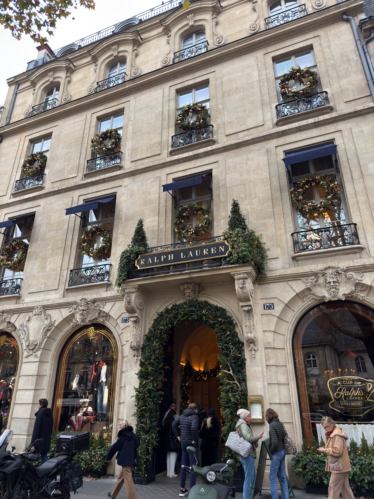 The Ralph Lauren store in Paris, France, is shown with holiday decorations. The building's facade is adorned with wreaths and greenery.