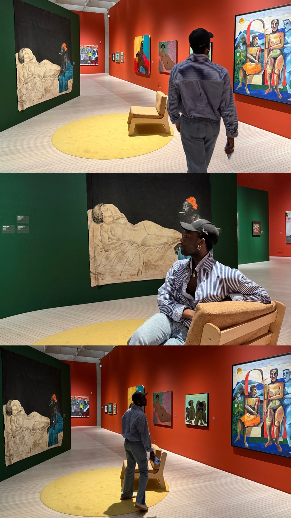 A Black man walks through a brightly colored art gallery, pausing to admire paintings and a large textured artwork on the wall. He sits on a chair to get a closer look at the art.