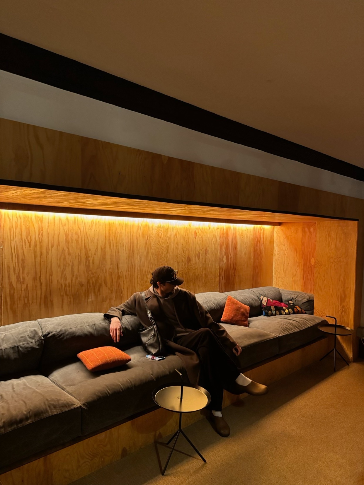 A man poses on a modern couch in a stylish interior. The photo showcases a minimalist aesthetic with a focus on design and fashion.