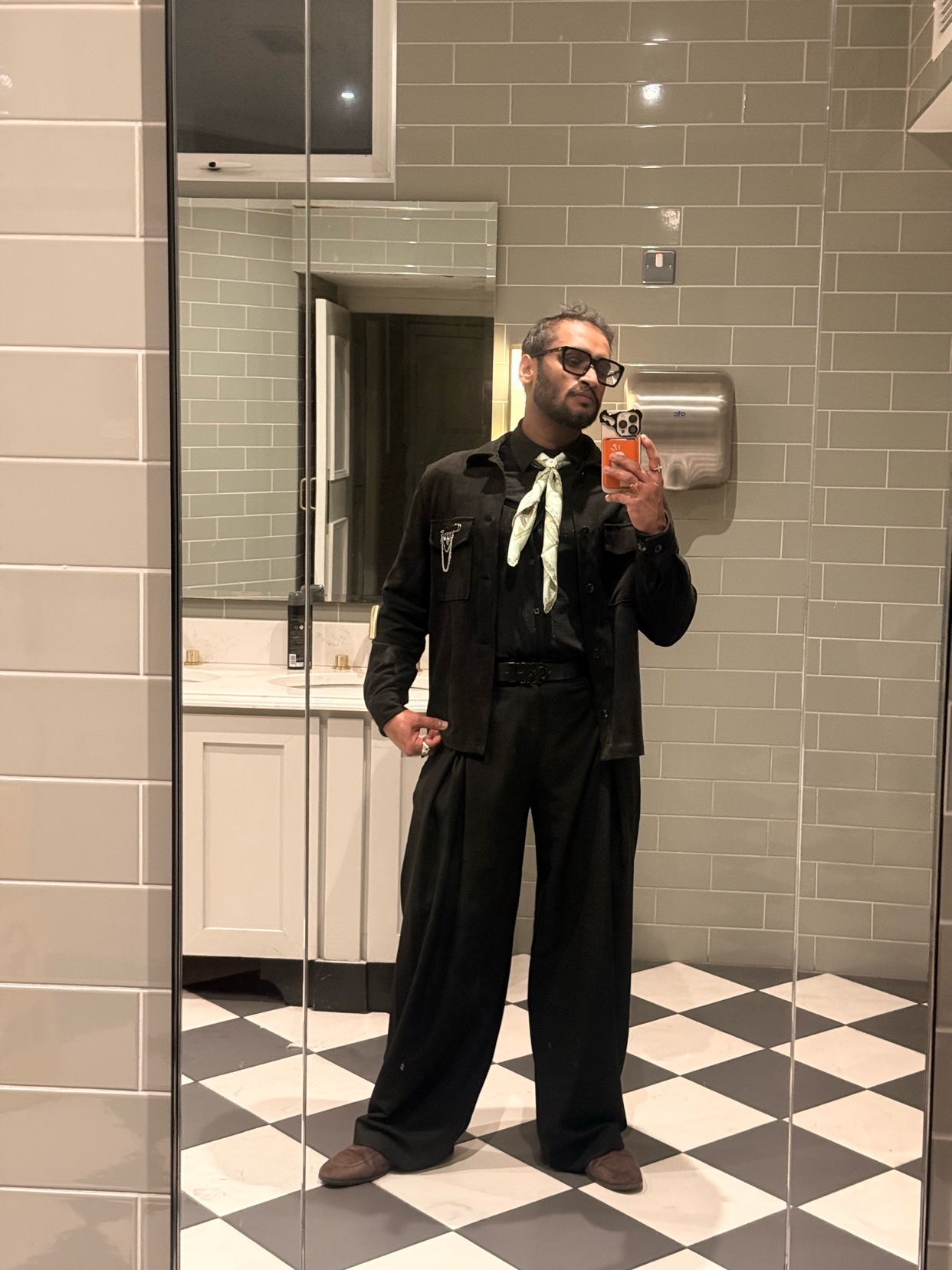 A man takes a mirror selfie in a stylish black suit. The photo showcases his fashion sense and modern style.