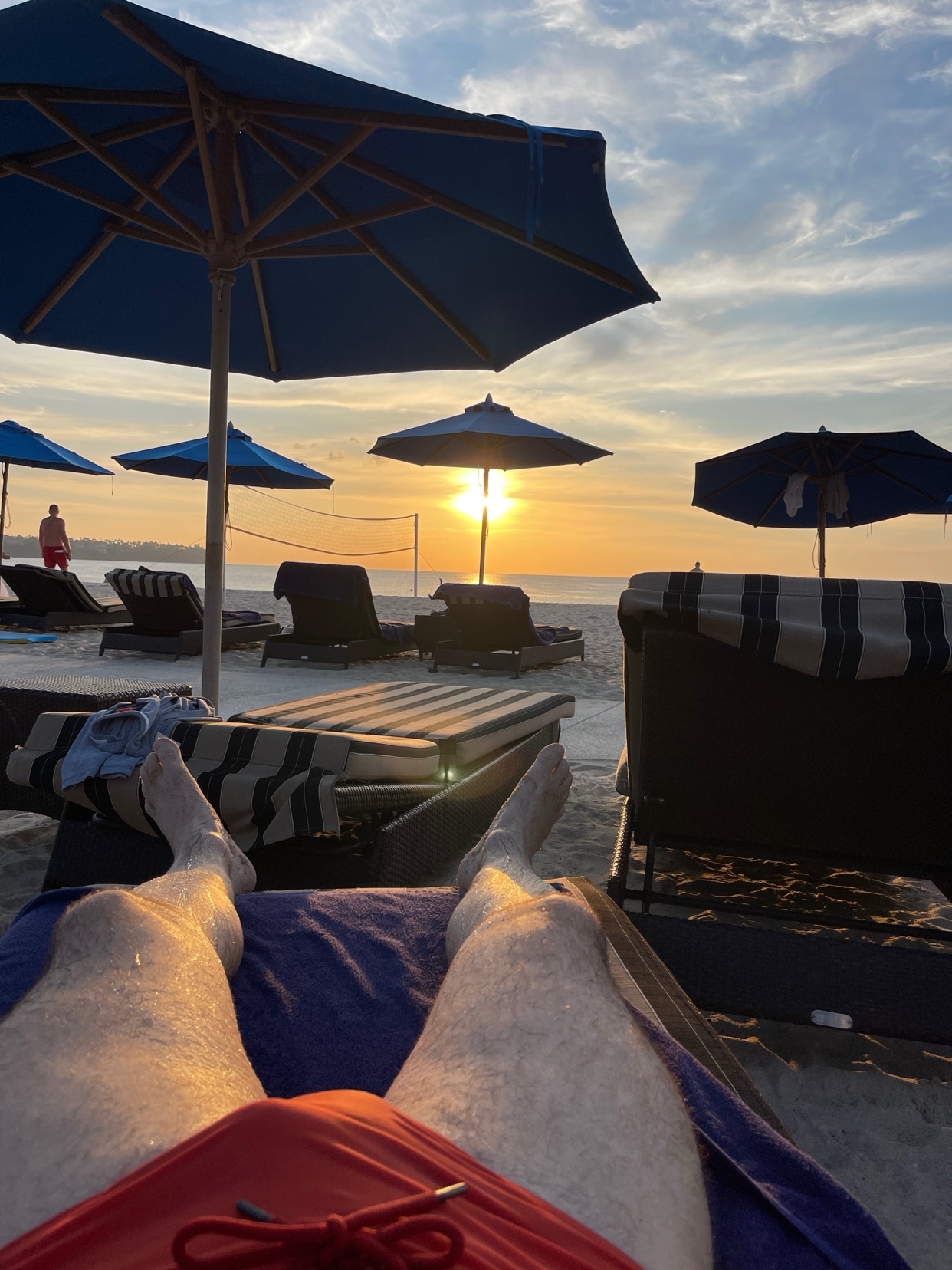A man relaxes on a beach chair, enjoying a beautiful sunset. The photo captures the serene atmosphere of a vacation.