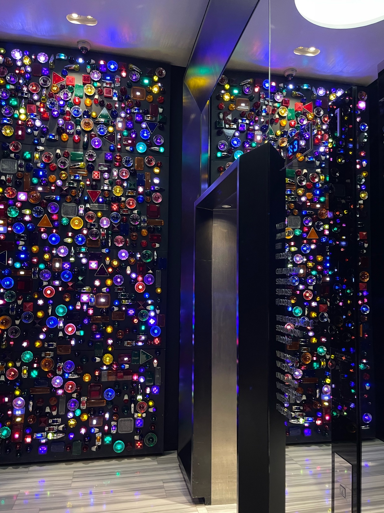 A visually striking lift hall in a hotel, featuring a wall adorned with colorful lights and geometric patterns. The design showcases a modern and artistic aesthetic.