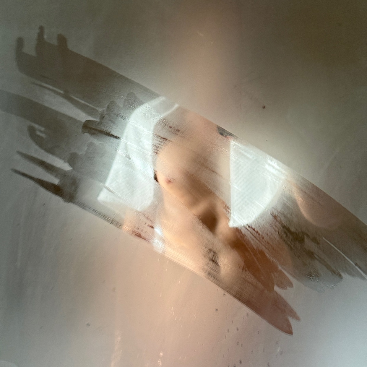 A steamy shower scene with a man's silhouette visible through the glass. The image captures the essence of a private moment.