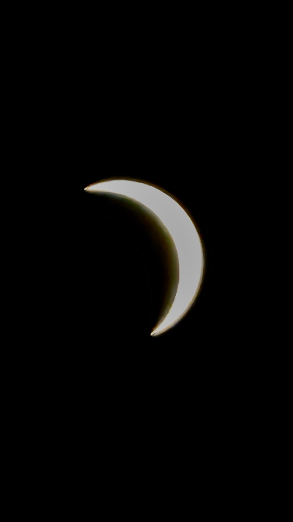 A partial solar eclipse is captured against a black sky, showing the sun as a bright crescent shape.