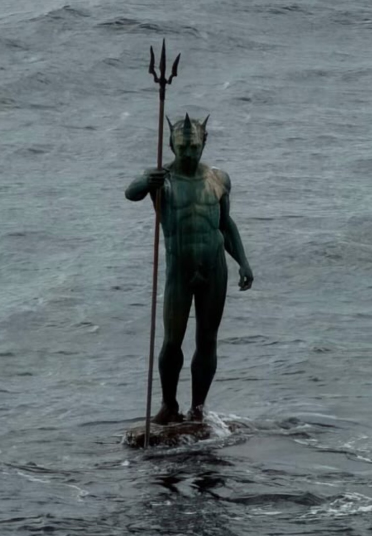 A bronze statue of Neptune, the Roman god of the sea, stands in the choppy ocean waters holding a trident.