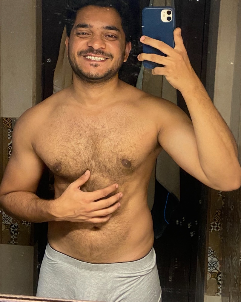 A man takes a mirror selfie, shirtless, showing off his physique. He is wearing gray underwear.