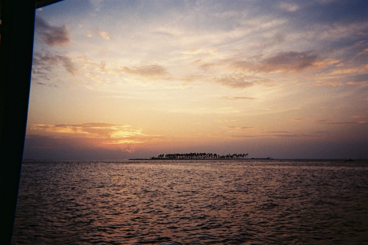 A beautiful sunset over the ocean in the Maldives. The sky is filled with colorful clouds, and the water reflects the light.