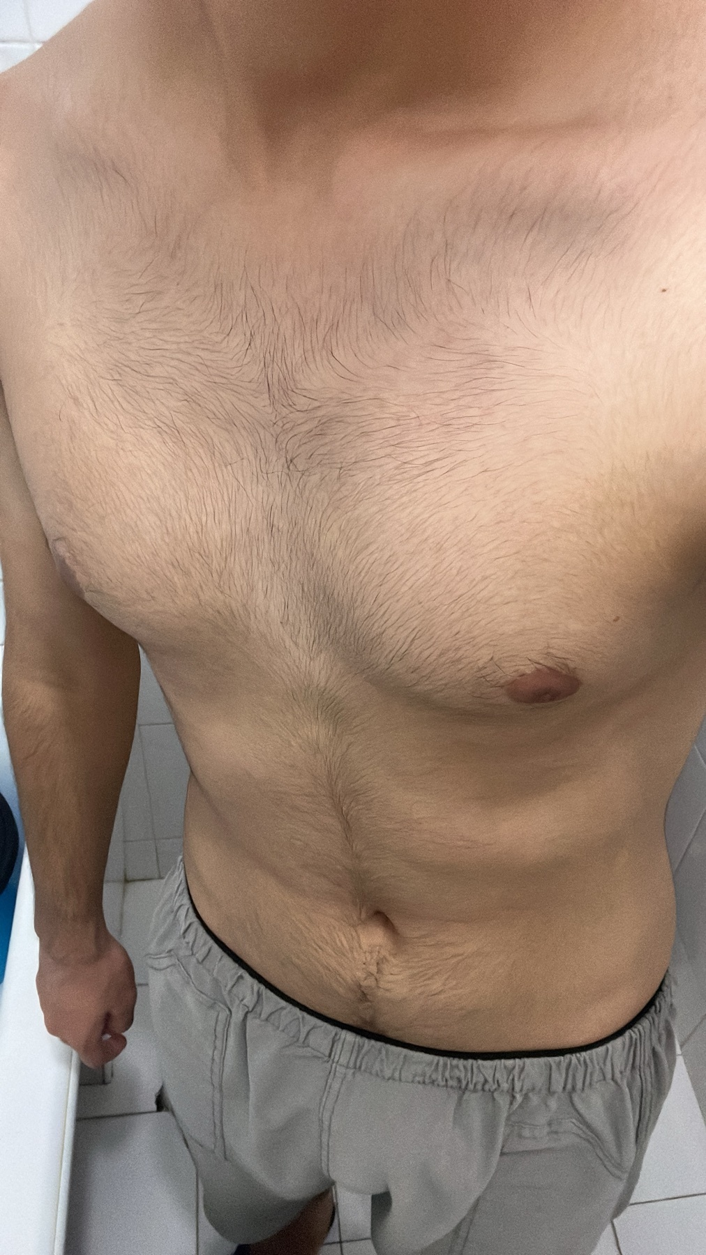 A shirtless man poses for a photo. The image focuses on his torso and upper body.