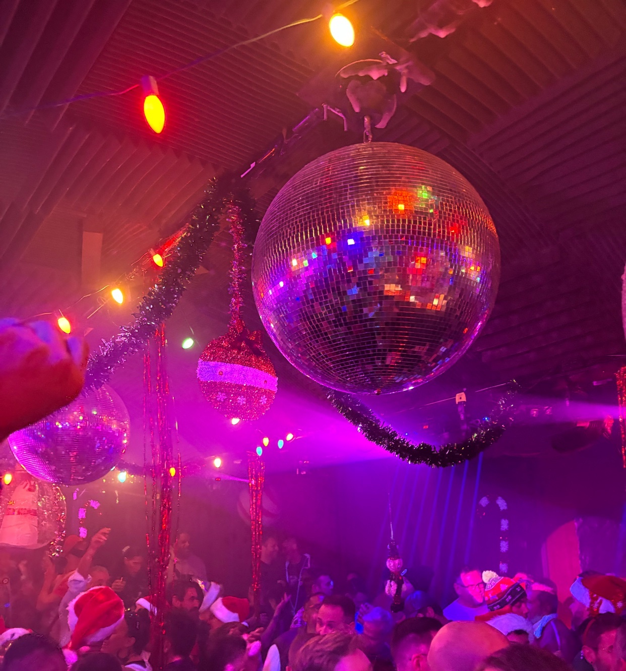 A vibrant nightclub scene with disco balls and festive decorations. The image captures the energy of a party with people enjoying themselves.
