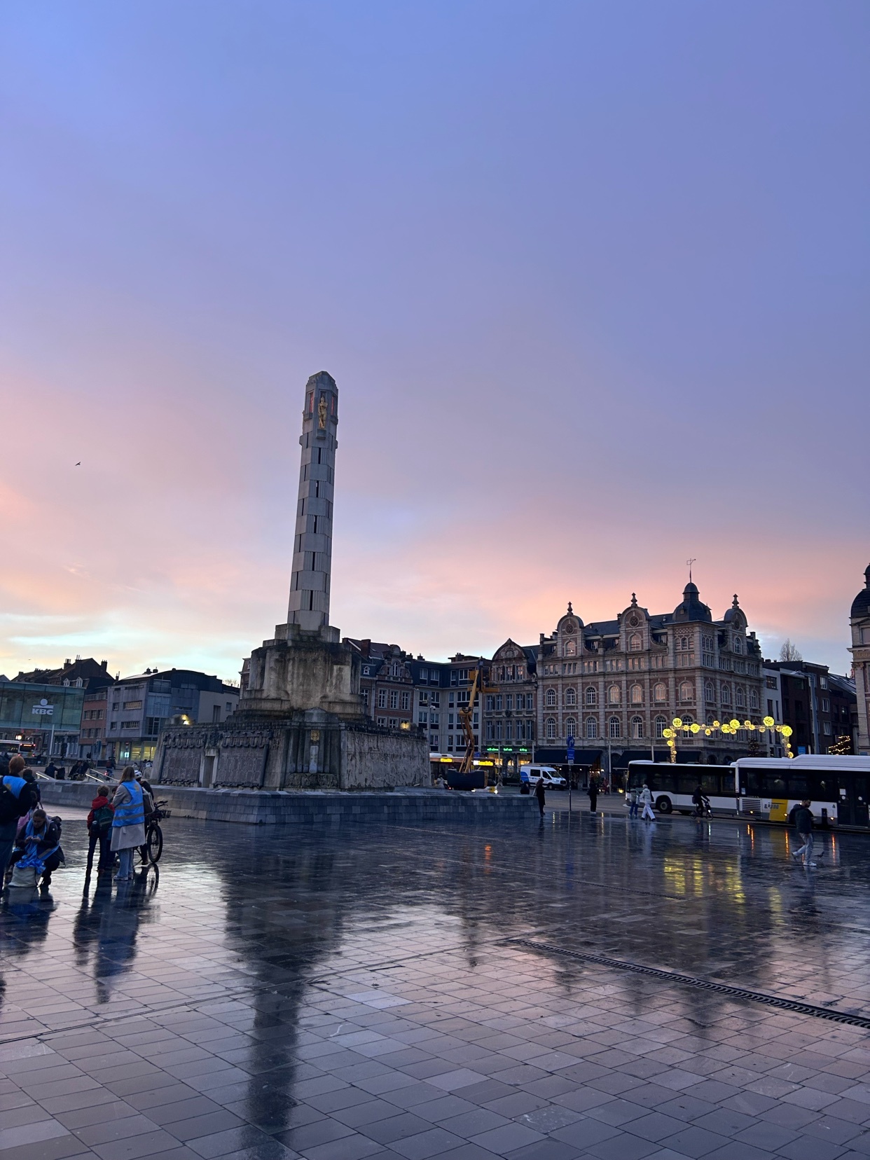 A beautiful cityscape with a monument in the center. The sky is a mix of pink and blue hues during sunset.